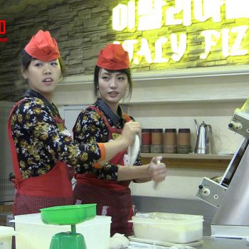 Two employees making pizza. <a href="https://www.facebook.com/dprk360/photos/basw.AboOIyC4YqqoKcVYKtiAmJAF6mDgIwIVAsaMZrx74PhjJfsO6Z9ktpWa6hl-nlj3Revw8Kz5IVoG23t_wx5F8O3DjiBFCutLgV2bhc_98O_xYvDJT7752j5RnfHKEcYczpgGDYBO88PMbUEMTZnBLrDe.412170968906737.269435646513604.322748121182356.322748181182350.322748117849023.322748167849018/322748121182356/?type=1&opaqueCursor=Abpq0Dm5e6CEgMGdfW0XmTUmNhlV4kRIiQATkCUpcx3rli-czg3M-GL04KIKuVtE_W4Muh_xidDqjGAlIUQty5L78i8CsmVGMW1magB6CvMxJ88_tcBiCCw7l3Eq0h44OEctaPJimaEU9Uov0sC0_ZYGfzmlEOsvu5KiWH0a8UPYYi7LWGnX2dXbLCbeUj6P6G6j8hd1nuaoLH2l4EHx5wNIWaGpFPztxQ2fNHF89trJriwXa-mSyGysJZhf9FDqsFwO_JfzwxQmLo4fV2fQBcwfKDlcscblCVnKOITFUJG--Zy7Ge4tr8Xohm9qQX-5fDjMw_T3NeAcqrKM3N5CAFYI60zWYk8HQfROw-owAD_iZ7LVCgKhjwwJjqw0FDoEs6WNxJvJHqDDPZ5fYzD6XXaHk3Ra7RscPSZPCPtFEhxgZh5FTfN1bASWrCc9QxMyTl8-qBf7usTcvfRkE0K-EJZgQp2OcZkin5wPrg5_UxHaesLBbK5_dAtRMMO5QfGX6Hkky_W6wDMl1V-1ZVJOYGX6gSWFtww_1pqJjOMg3qEb9myD2pvobAb3CSKvMgfvHg7nvlo3b5CoPgJSgzCXoOKKqKgemR9pLVu_CXz6U3PxaRhLea_PXgcLFL_XOyRRUK4&theater" target="_blank">Original photo</a> Staff pizza restaurant Pyongyang